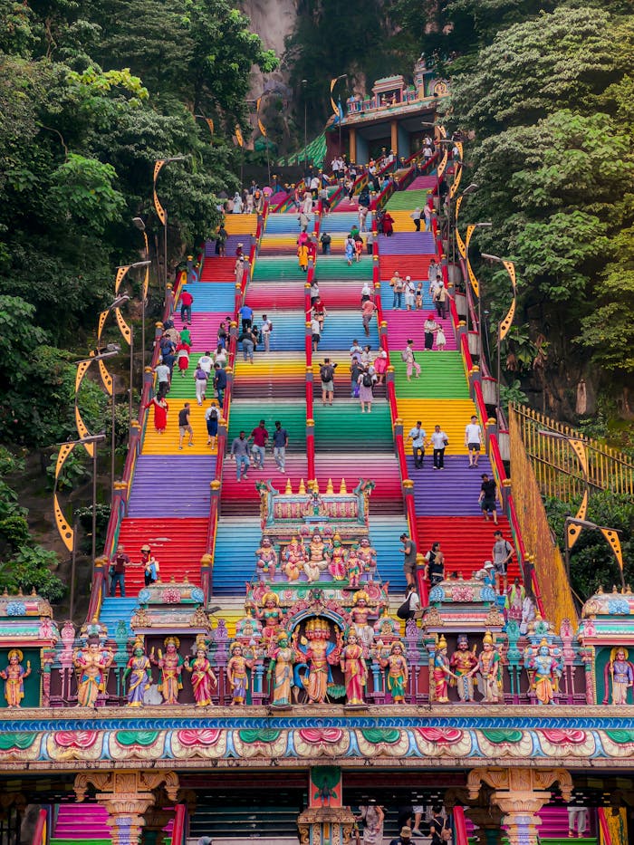 Colorful stairs at Batu Caves, Malaysia with visitors climbing. Iconic cultural landmark.