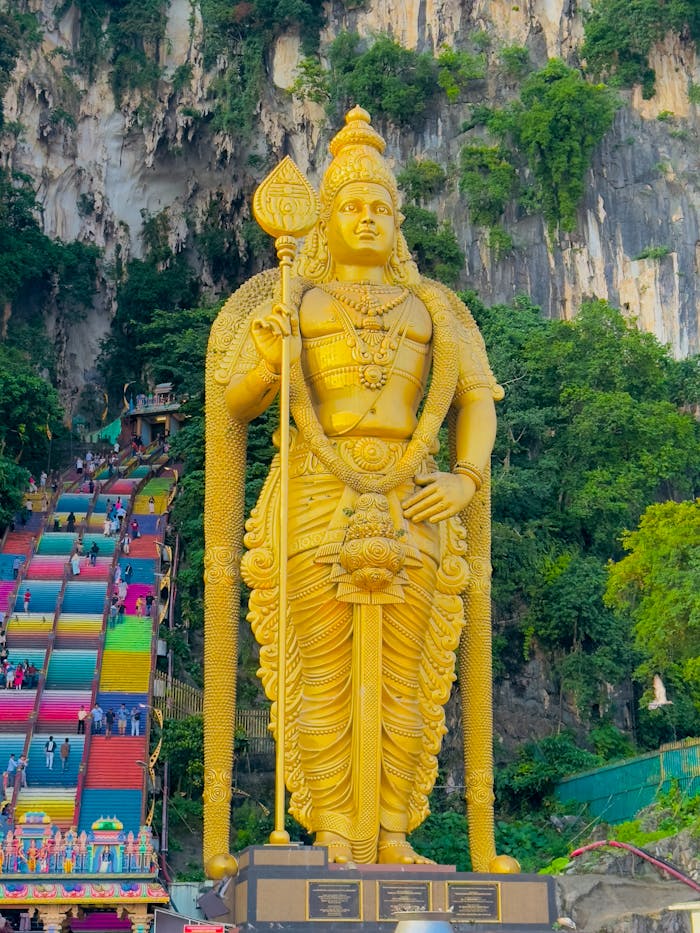 Majestic golden statue of Lord Murugan at the colorful Batu Caves entrance in Malaysia.